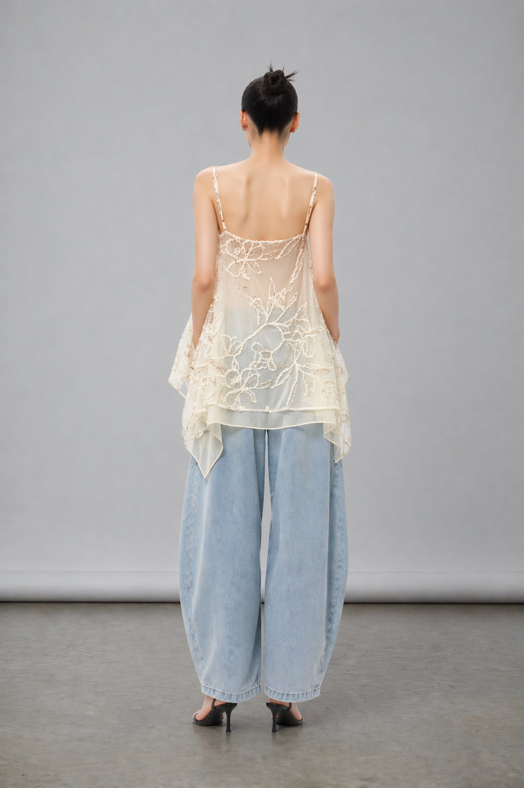 Asian Model wearing a sheer top and light blue pants against a gray background