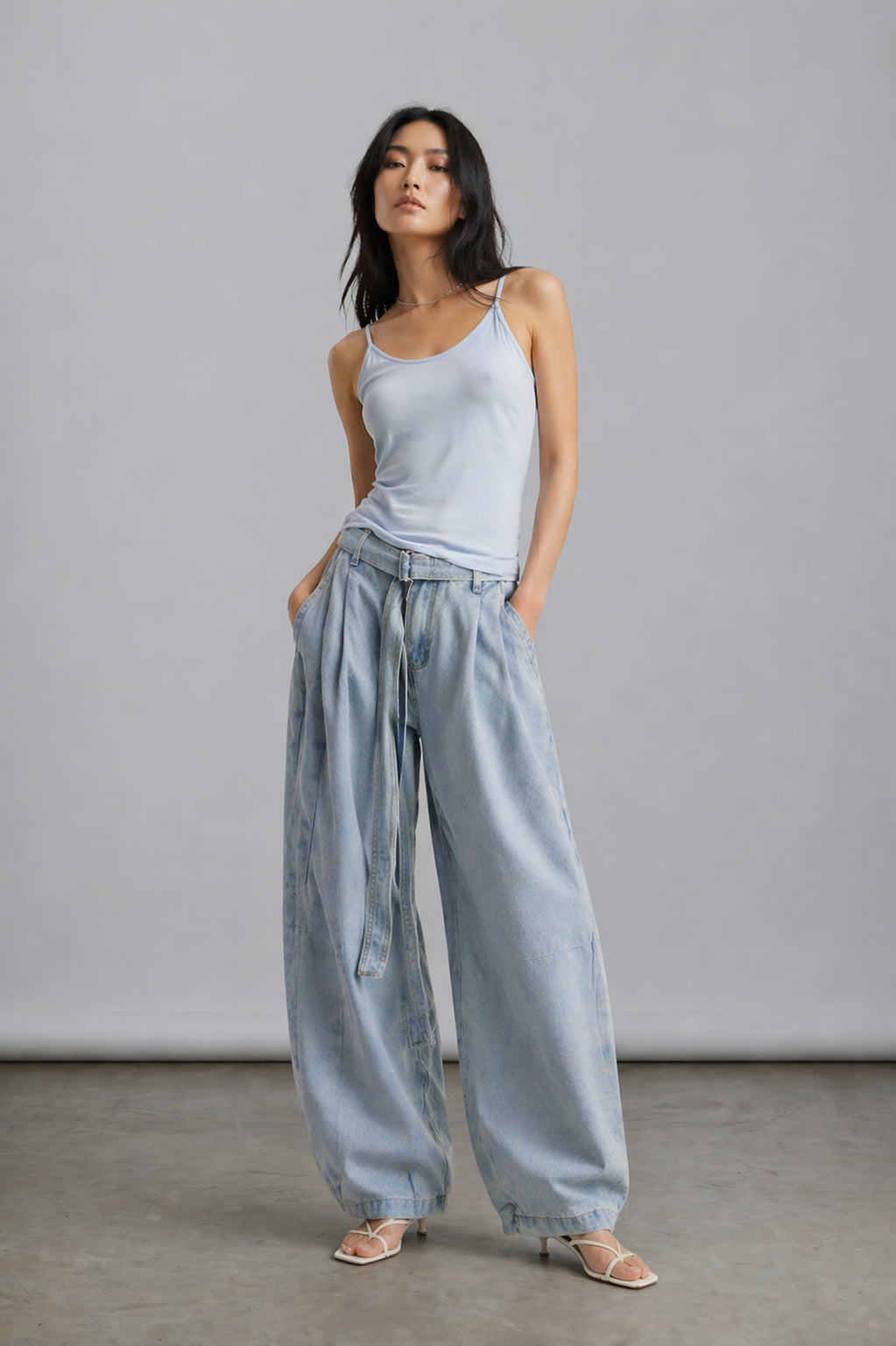 Woman wearing a light blue tank top and wide-leg pants against a plain background
