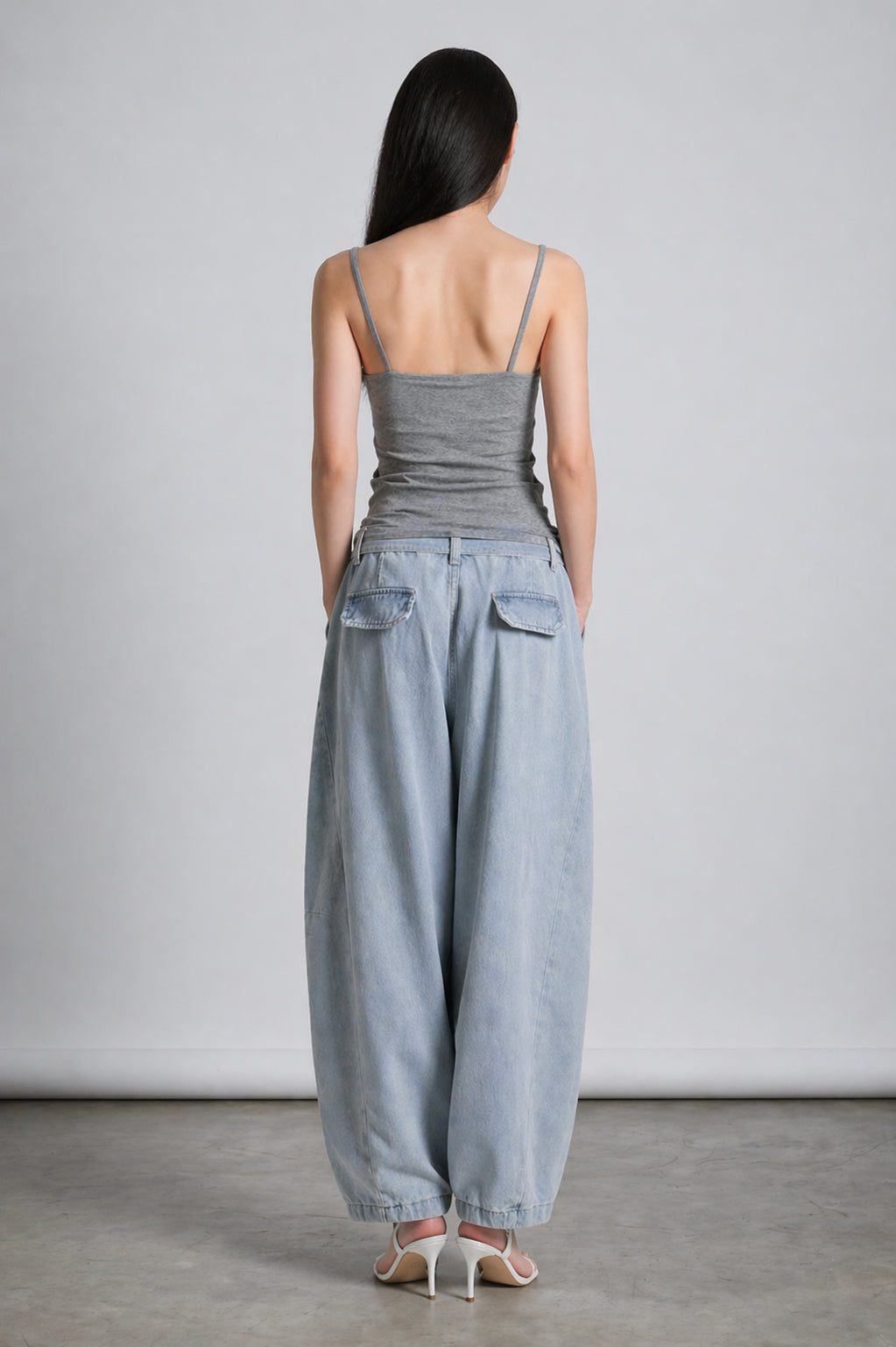 Asian Woman wearing a gray tank top and light blue wide-leg pants against a plain background