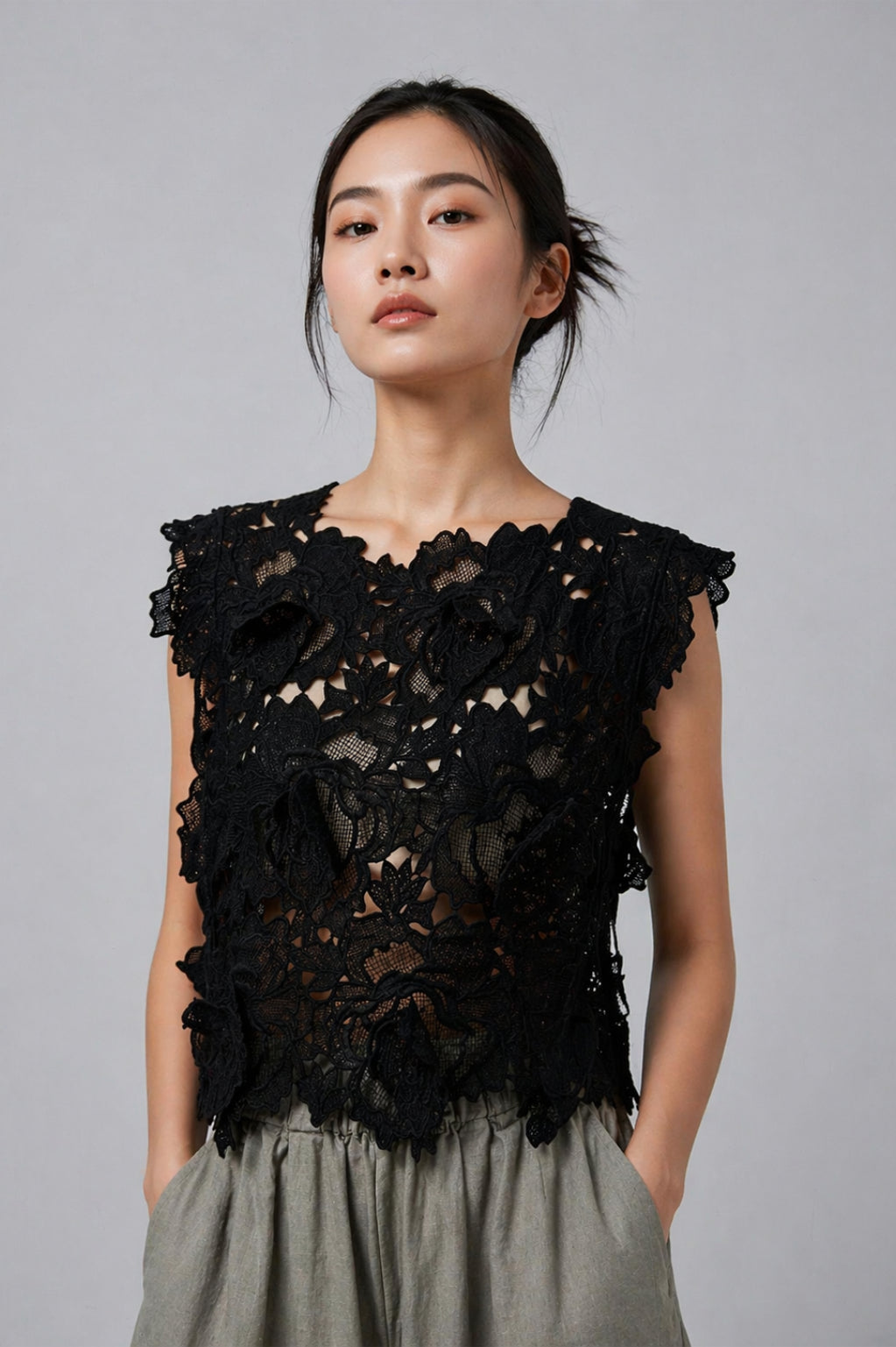 Woman wearing a black lace top against a gray background