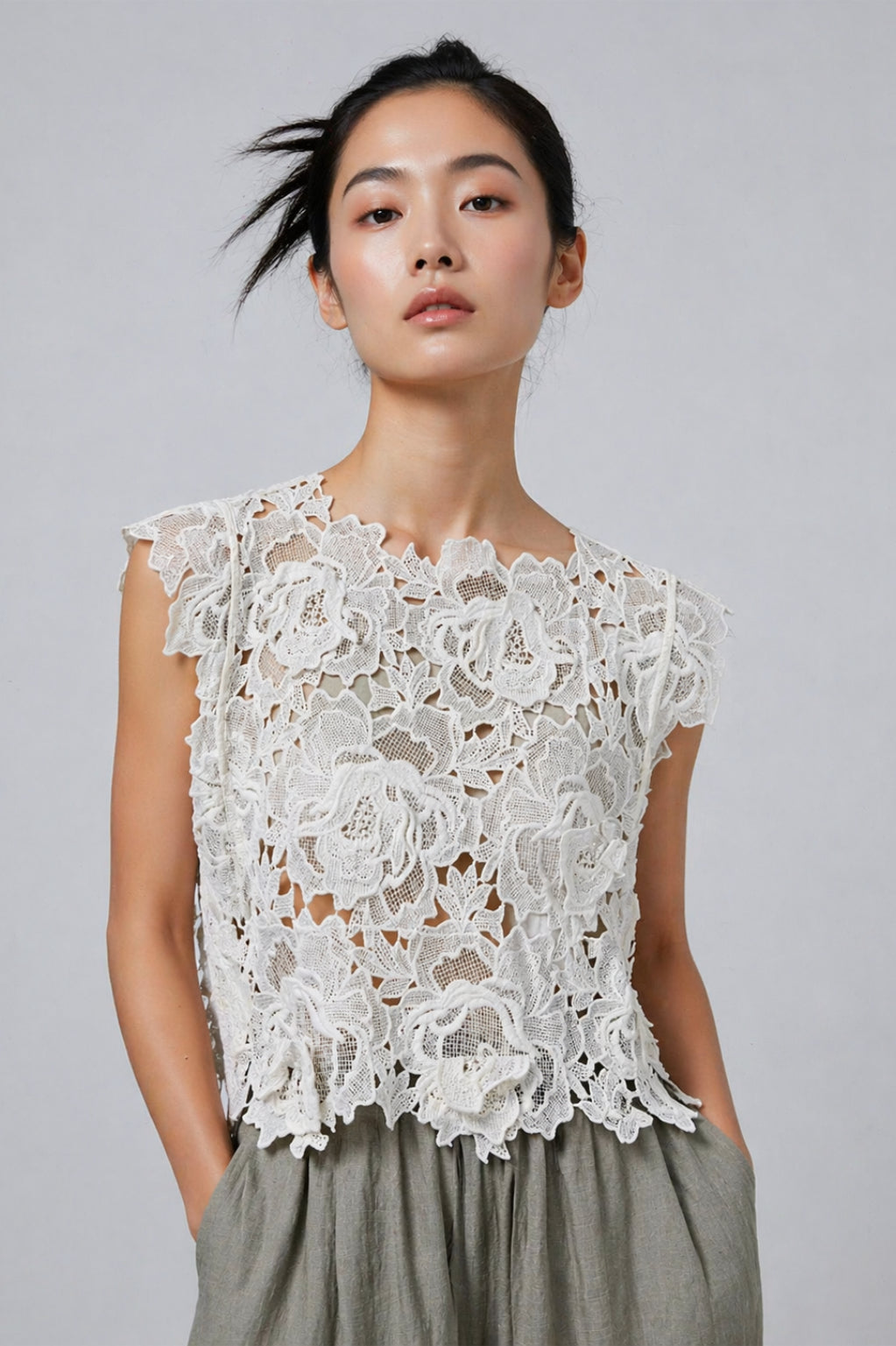 Woman wearing a white lace top against a gray background