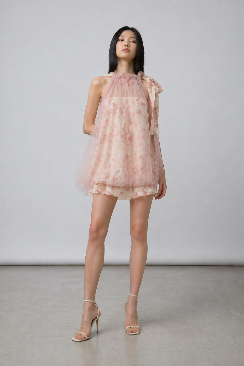 Woman wearing a pink floral dress against a plain background