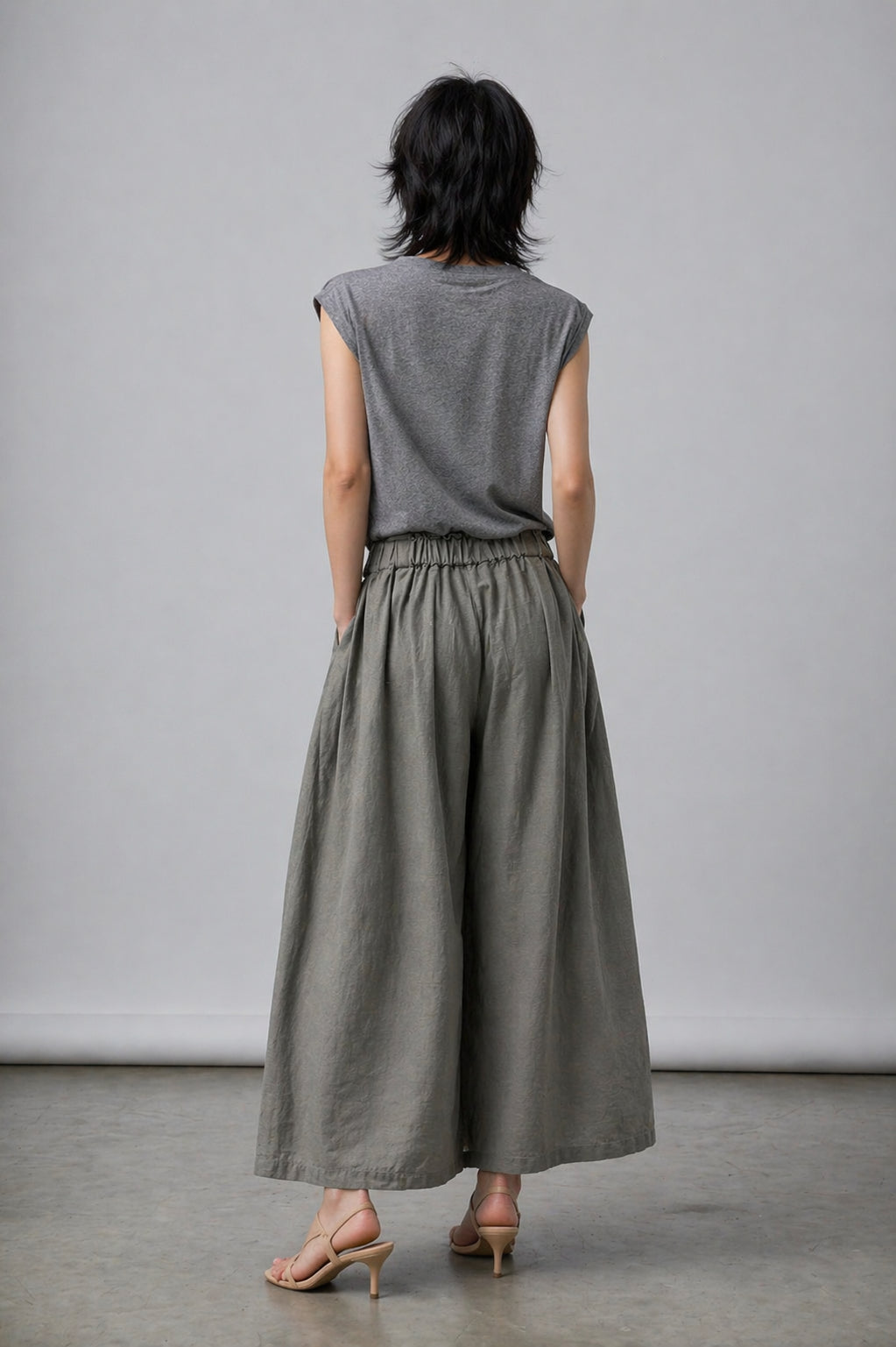 Person wearing a gray sleeveless top and wide-leg pants against a plain background